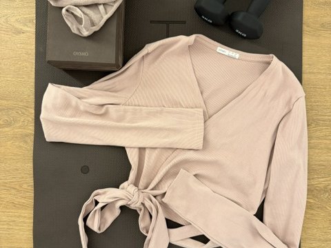 Esterilla con una chaqueta cruzada de punto, un bloque y unas mancuernas