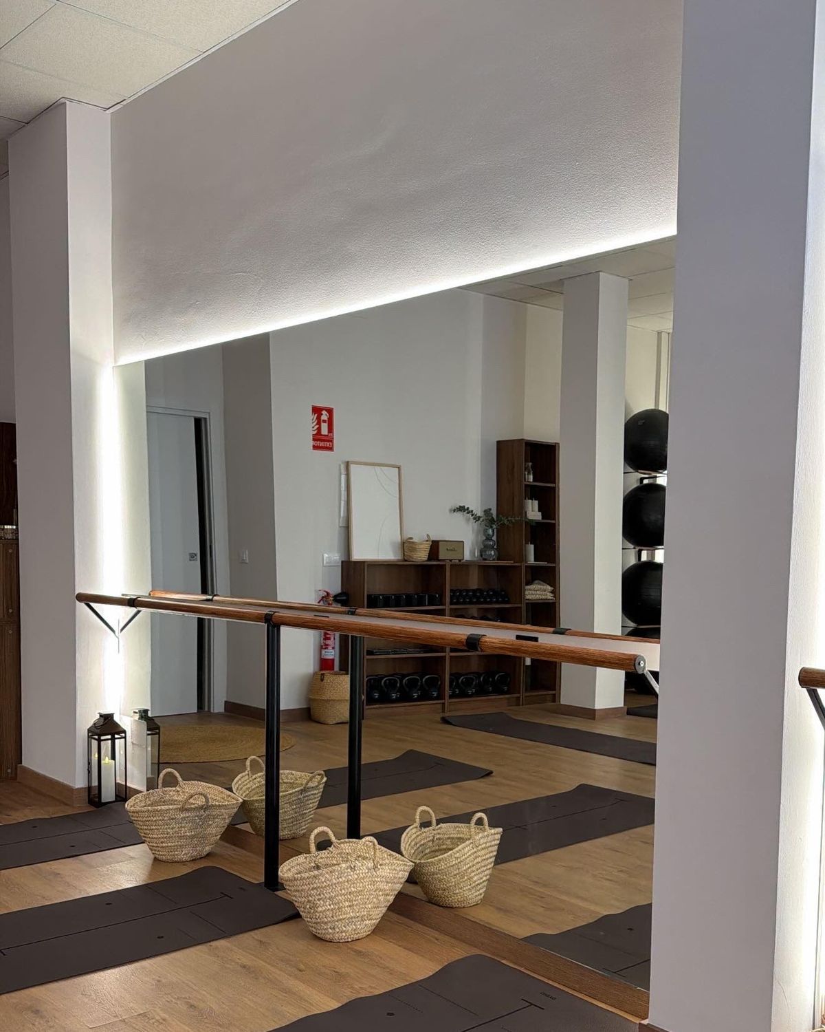 La sala del estudio: barras de madera, esterillas en el suelo y cestas de esparto, reflejadas en el espejo
